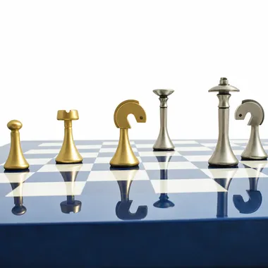 Gold and silver brass pieces lined up on the blue chess board