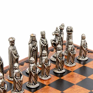 Detail of silver-toned medieval pieces lined up on the faux leather board