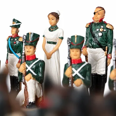 Chess pieces showing soldiers in green uniform and queen in white dress
