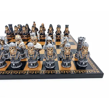 Hand-painted skull chess pieces lined up on the black and gold board