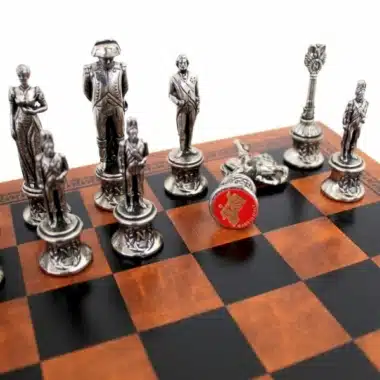 Silver-toned Napoleon chess pieces in metal arranged on the chessboard