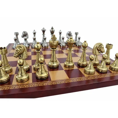 Staunton pieces in gold and silver metal, close-up on red and gold chess board